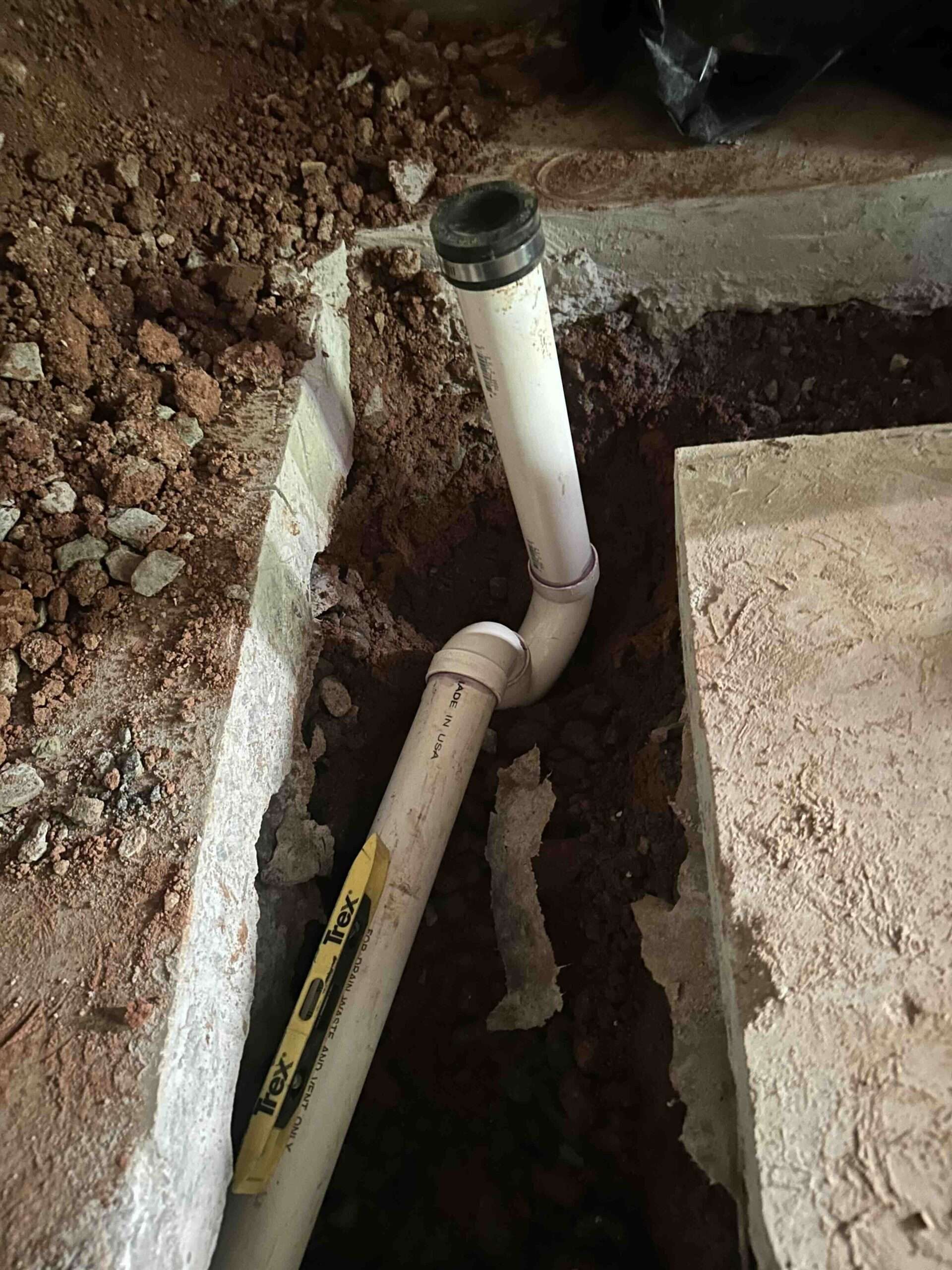 Sewer line installation in progress with exposed PVC pipes and surrounding dirt, showcasing plumbing work by Azerplumb in Cumming, Georgia.