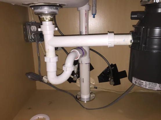 Garbage disposal unit installed under kitchen sink with plumbing connections, illustrating compatibility with septic systems.