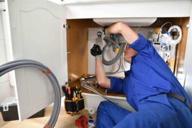 Plumber performing drain cleaning under a sink with advanced tools, emphasizing professional plumbing services in Milton, GA.