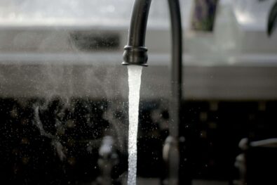 Close-up of a black faucet with water flowing, illustrating faucet functionality and installation services offered by Azerplumb in Marietta, GA.