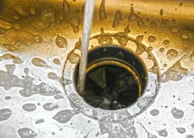 Water flowing into a kitchen sink drain with visible bubbles, illustrating a functional garbage disposal system in a domestic setting.