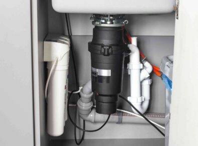 Garbage disposal unit installed under kitchen sink with plumbing connections, showcasing efficient setup for reliable kitchen waste management in Dunwoody, GA.