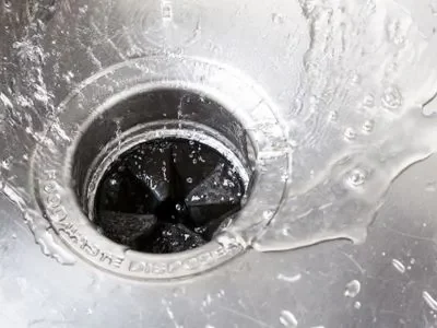 Garbage disposal with water flowing, illustrating the cleaning process and maintenance tips for eliminating odors and clogs.