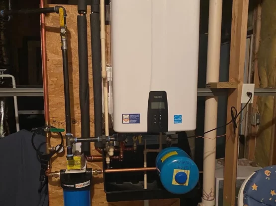 Navien tankless water heater installed on a wall with connected pipes and water filtration system, illustrating essential components for maintenance and optimal performance.