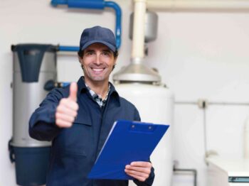 Plumber giving a thumbs up while holding a clipboard in a plumbing setting, symbolizing the importance of regular plumbing maintenance and services offered by Azerplumb.