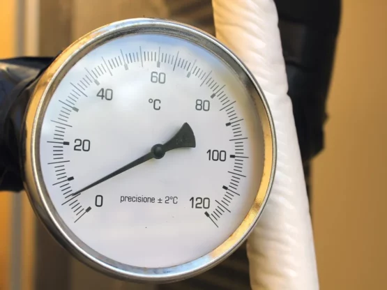 Water heater temperature gauge displaying Celsius readings, indicating optimal setting around 120 degrees to ensure safety and energy efficiency.