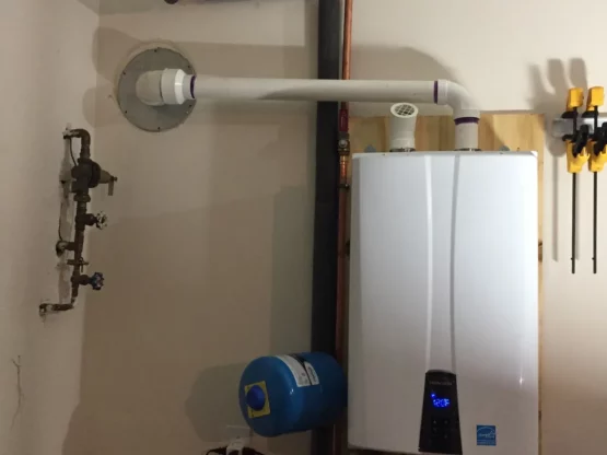 Water heater and expansion tank installation in a plumbing system, featuring a blue expansion tank and connected pipes.